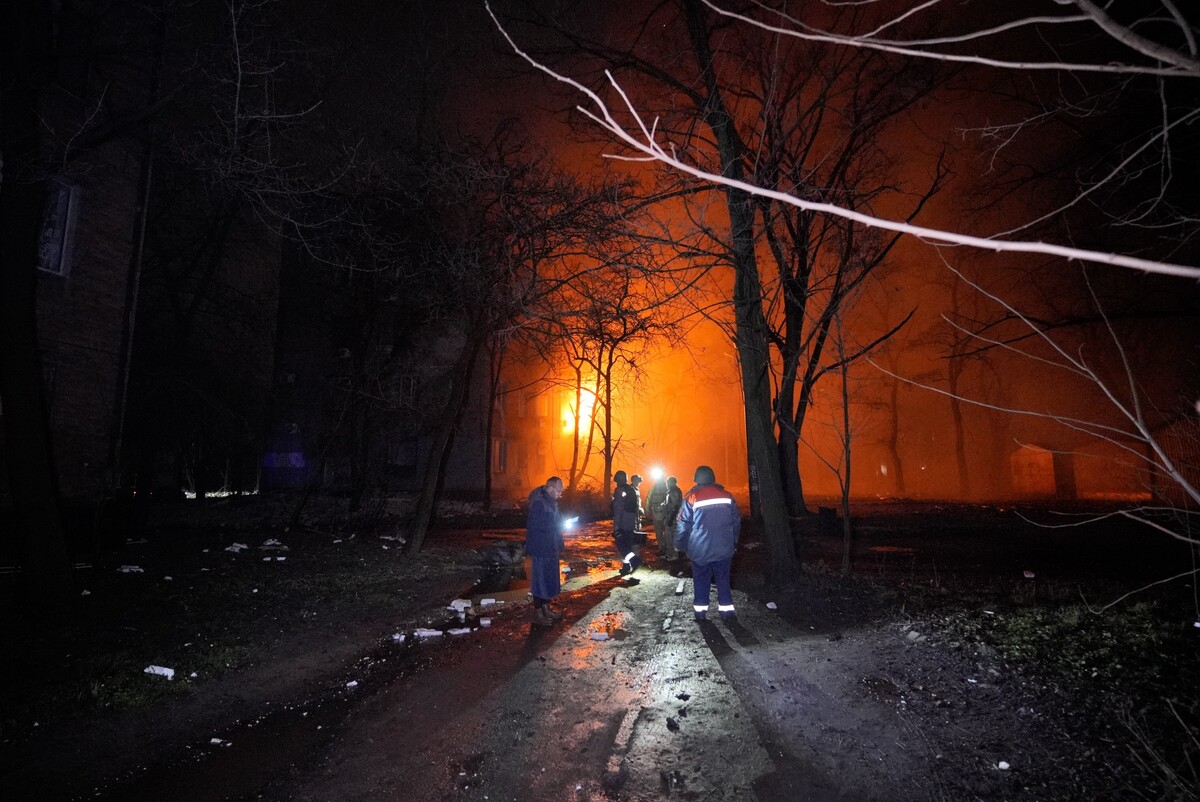 People stand outside a burning building after a Russian strike in Kryvyi Rih, Ukraine, Thursday, Jan. 8, 2026. (AP Photo/Mykola Myrnyi)