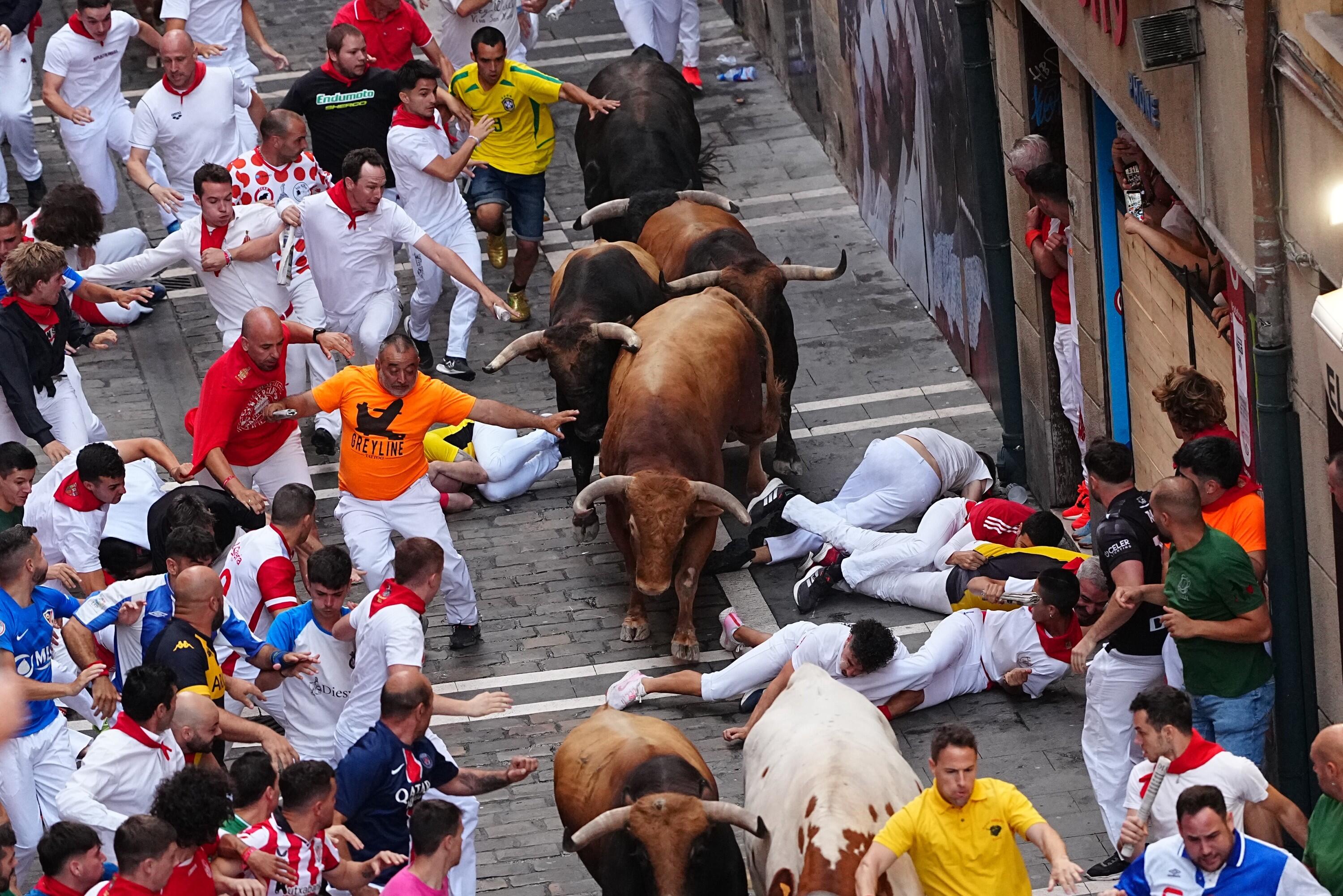 Revelers run alongside La Palmosilla's fighting bull during the sixth running of the bulls at the San Fermín festival in Pamplona, Spain, Sunday, July 12, 2026. (AP Photo/Miguel Oses)