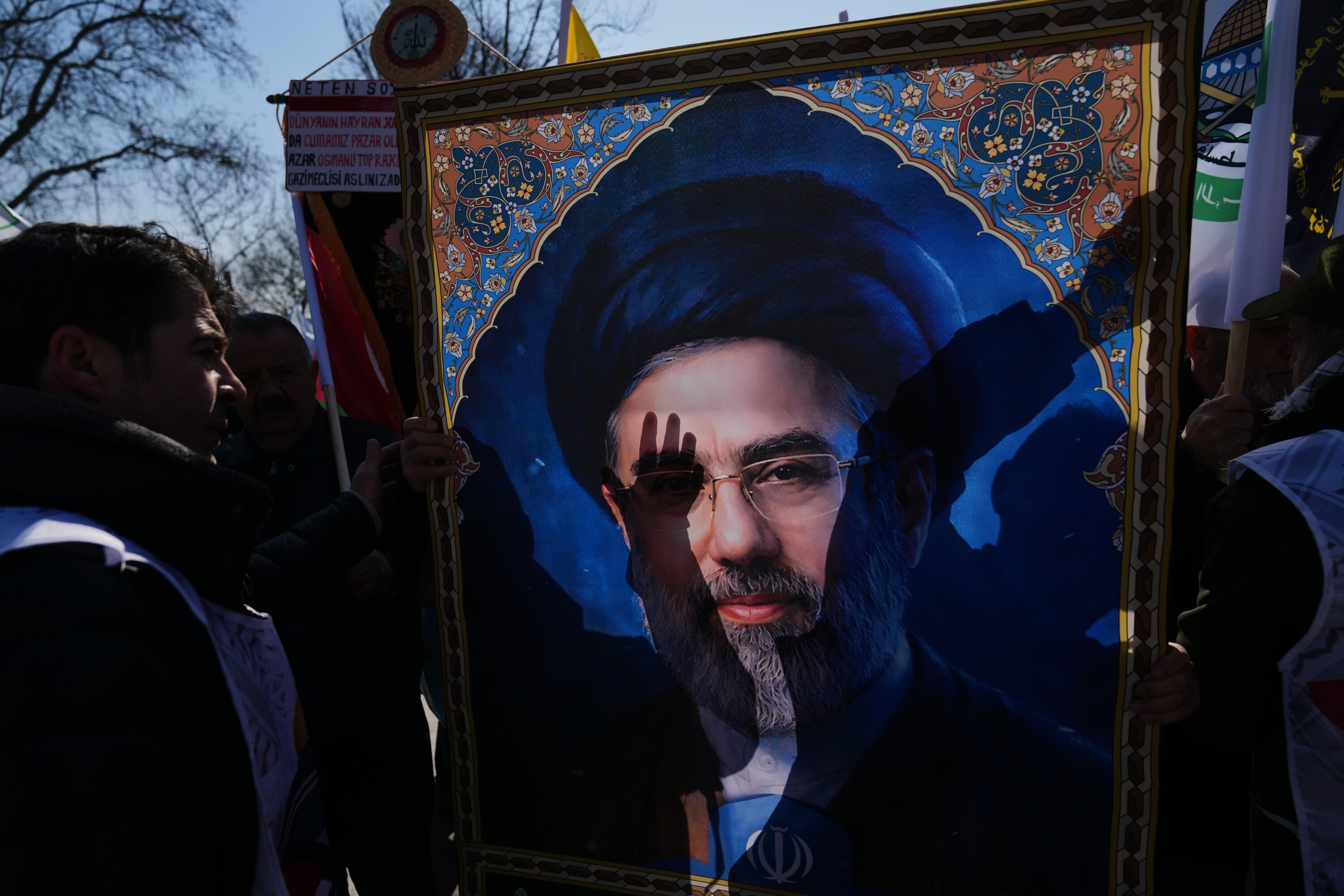 People hold a portrait of new Iranian Supreme Leader Ayatollah Mojtaba Khamenei as they march during a protest against Israel and the U.S., in Istanbul, Friday, March 13, 2026. (AP Photo/Francisco Seco)