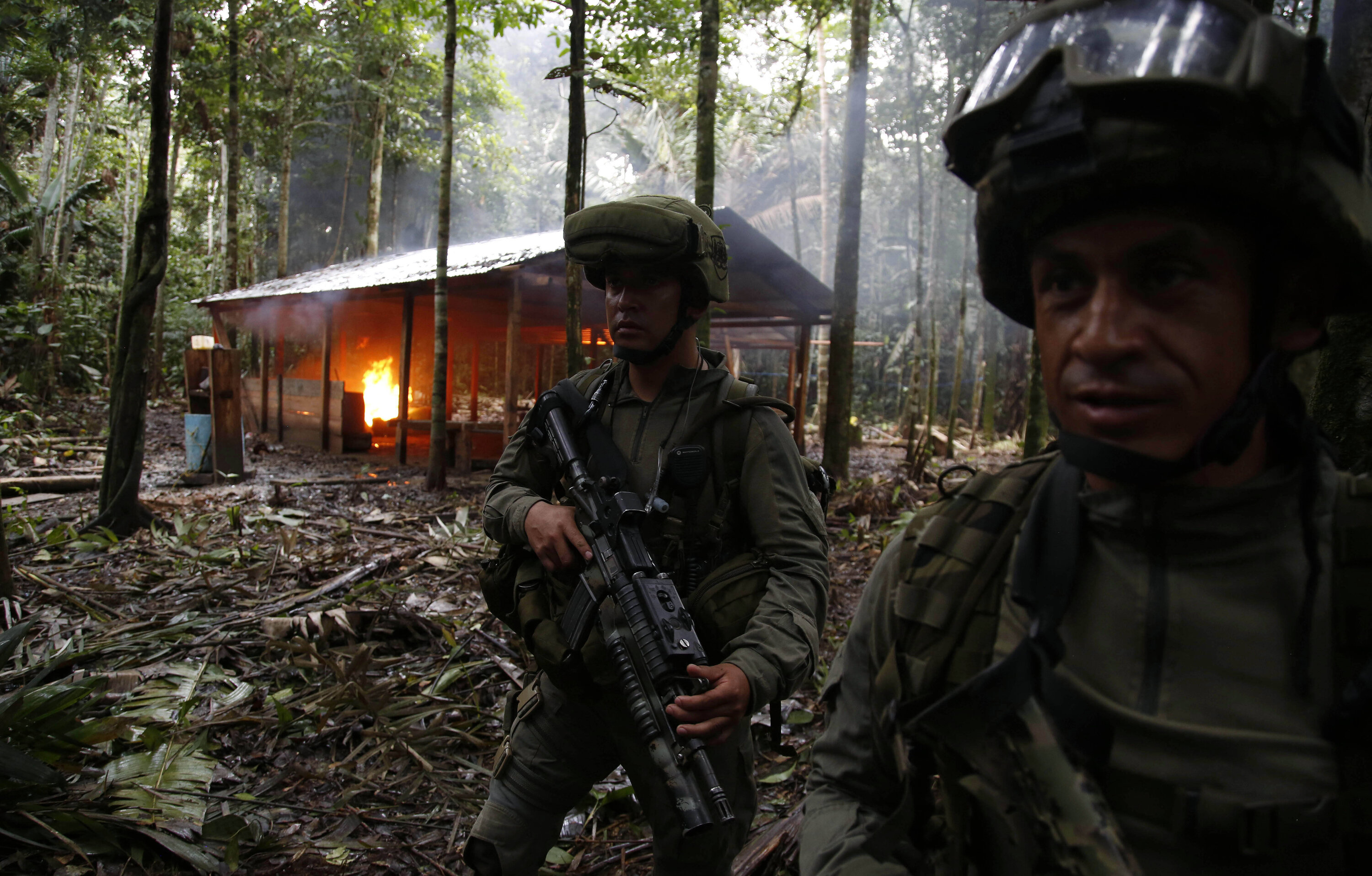 Anti-narcotics police officers stand guard in front of a burning cocaine lab in Calamar, Guaviare state, Colombia, Tuesday, Aug. 2, 2016. Police seized cocaine and chemicals at the lab, which according to the commander of the anti-narcotics police Gen. Jose Mendoza would have made it from Colombia to Brasil, then to Venezuela and finally into Europe. About 104 labs have been destroyed by the police during  the las five days. (AP Photo/Fernando Vergara)