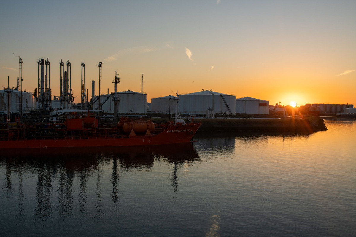 A picturesque view of an industrial port and tanker ship at sunrise, creating a stunning silhouette.