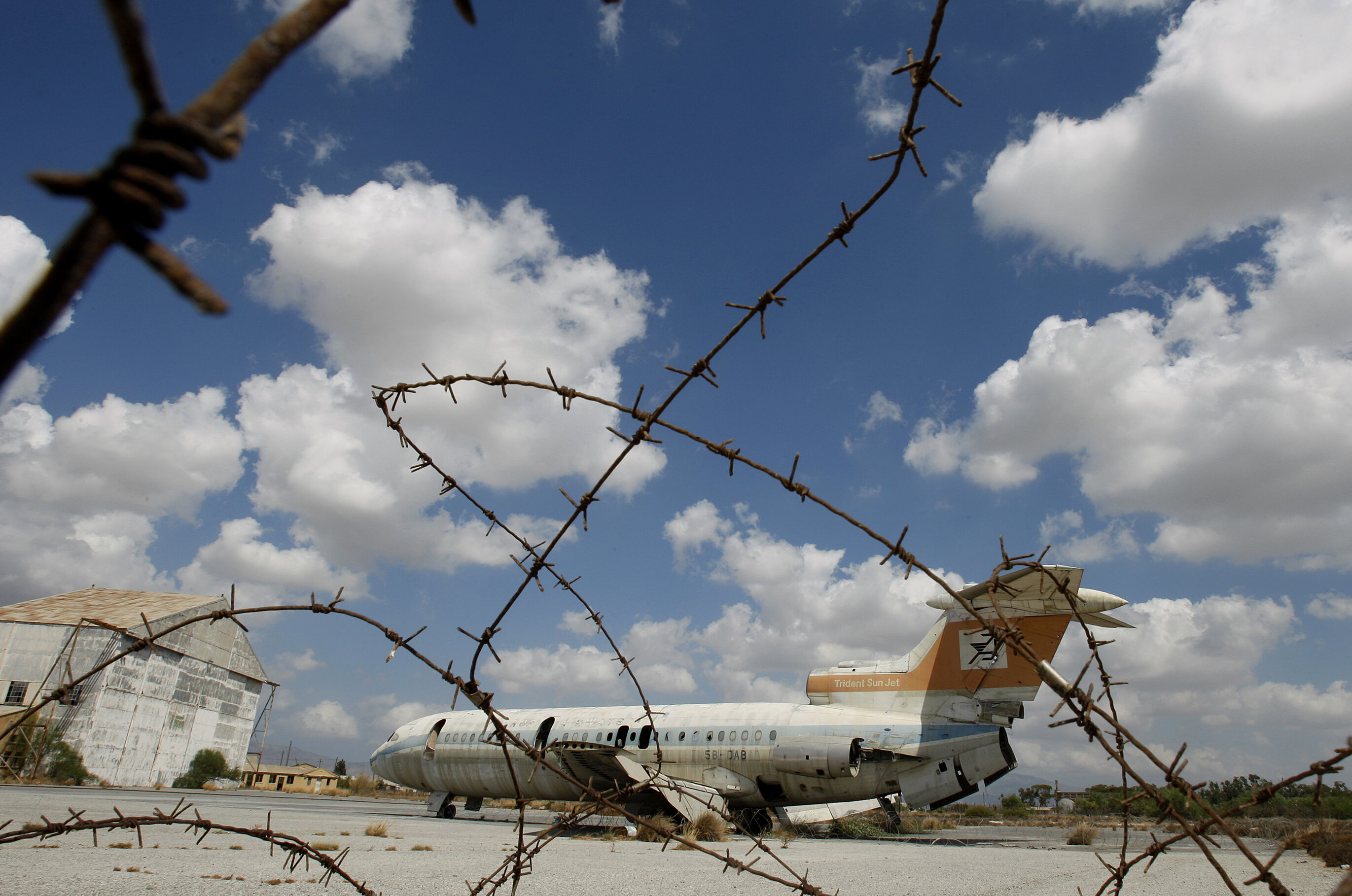 A destroyed Cyprus airways plane behind barbed wire at the war-torn UN buffer zone at the abandoned Nicosia airport during a rare media tour of the defunct facility Tuesday, Sept. 14, 2010. The airport has remained frozen in time after being shut down in 1974 when a coup by supporters of union with Greece prompted Turkey to invade and split the island into a breakaway Turkish Cypriot north and an internationally recognized Greek Cypriot south. The airport was the scene of fierce battles during the invasion and was declared a UN protected area. It now straddles the UN controlled buffer zone separating the rival communities and is home to the UN peacekeeping force's headquarters. It is also the venue for ongoing talks aimed at reunification. But the airport's once bustling main terminal building built in 1968 and hailed as one of the region's best at that time remains under lock and key, ravaged by time and inhabited by pigeons. (AP Photo/Petros Karadjias)