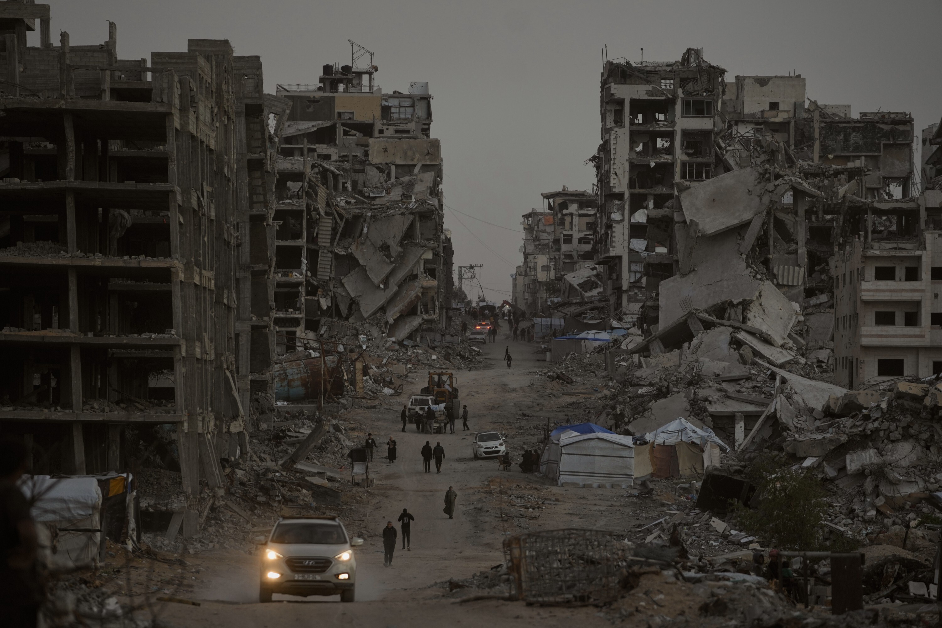 Palestinians walk through the destruction in the Al-Karama neighborhood of Gaza City Sunday, Nov. 30, 2025. (AP Photo/Jehad Alshrafi)