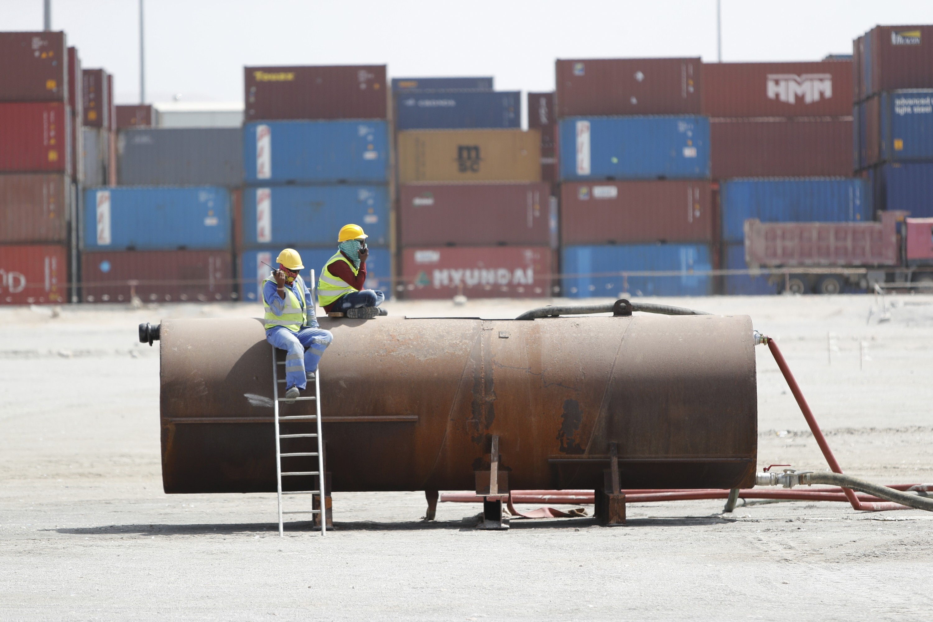 Workers sit in front of shipping containers on the dock at the seaport of Berbera in Somaliland, a breakaway region of Somalia, Thursday, Feb. 10, 2022. (AP Photo/Brian Inganga)