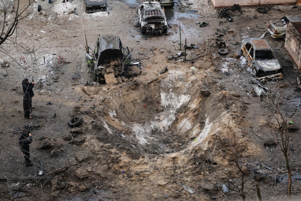 People stand near a crater and damaged cars after a Russian attack in Zaporizhzhia, Ukraine, Wednesday, Jan. 28, 2026. (AP Photo/Kateryna Klochko)