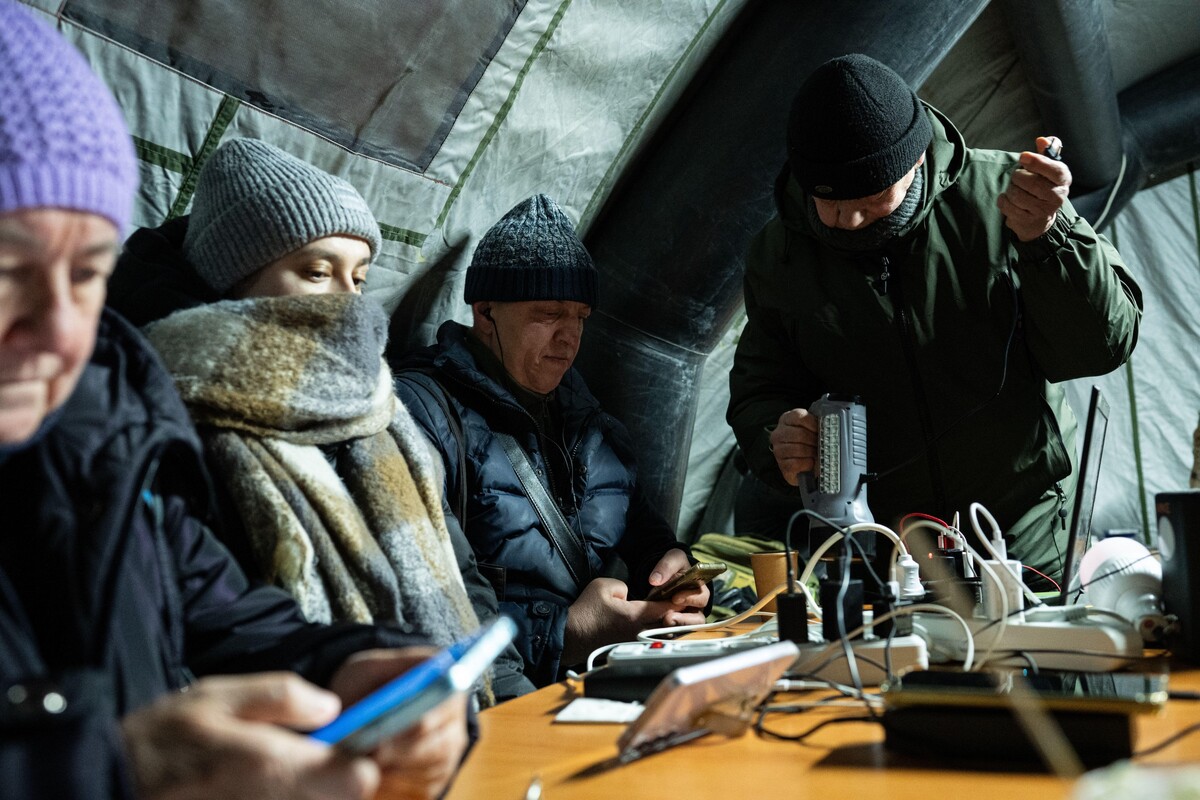 People warm up and charge their mobile devices during a power outage caused by Russia's regular air attacks on the country's energy sector in Kyiv, Ukraine, Sunday, Jan. 18, 2026. (AP Photo/Danylo Antoniuk)