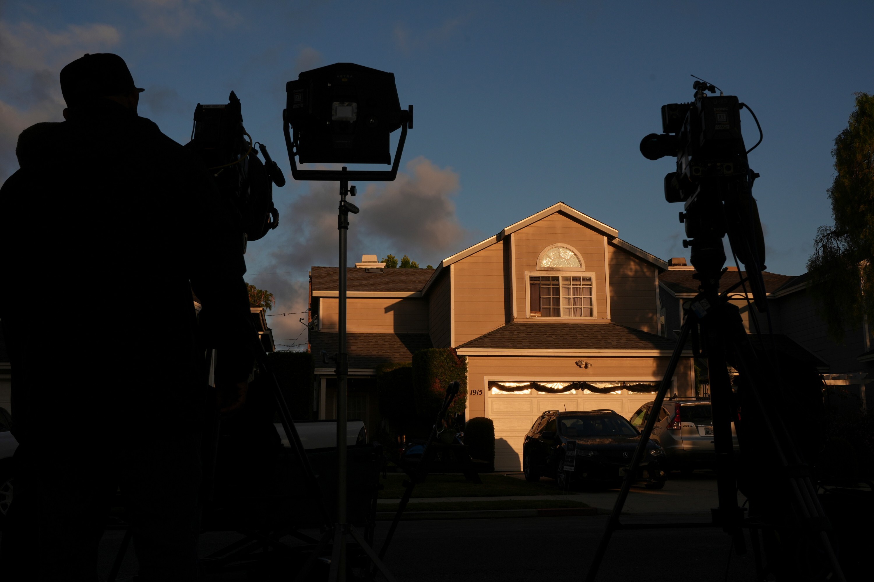 A cameraman stands, Sunday, April 26, 2026, in front of a house in Torrance, Calif., connected to Cole Tomas Allen, who was identified as the shooting suspect at the White House Correspondents Dinner the night before. (AP Photo/Damian Dovarganes)